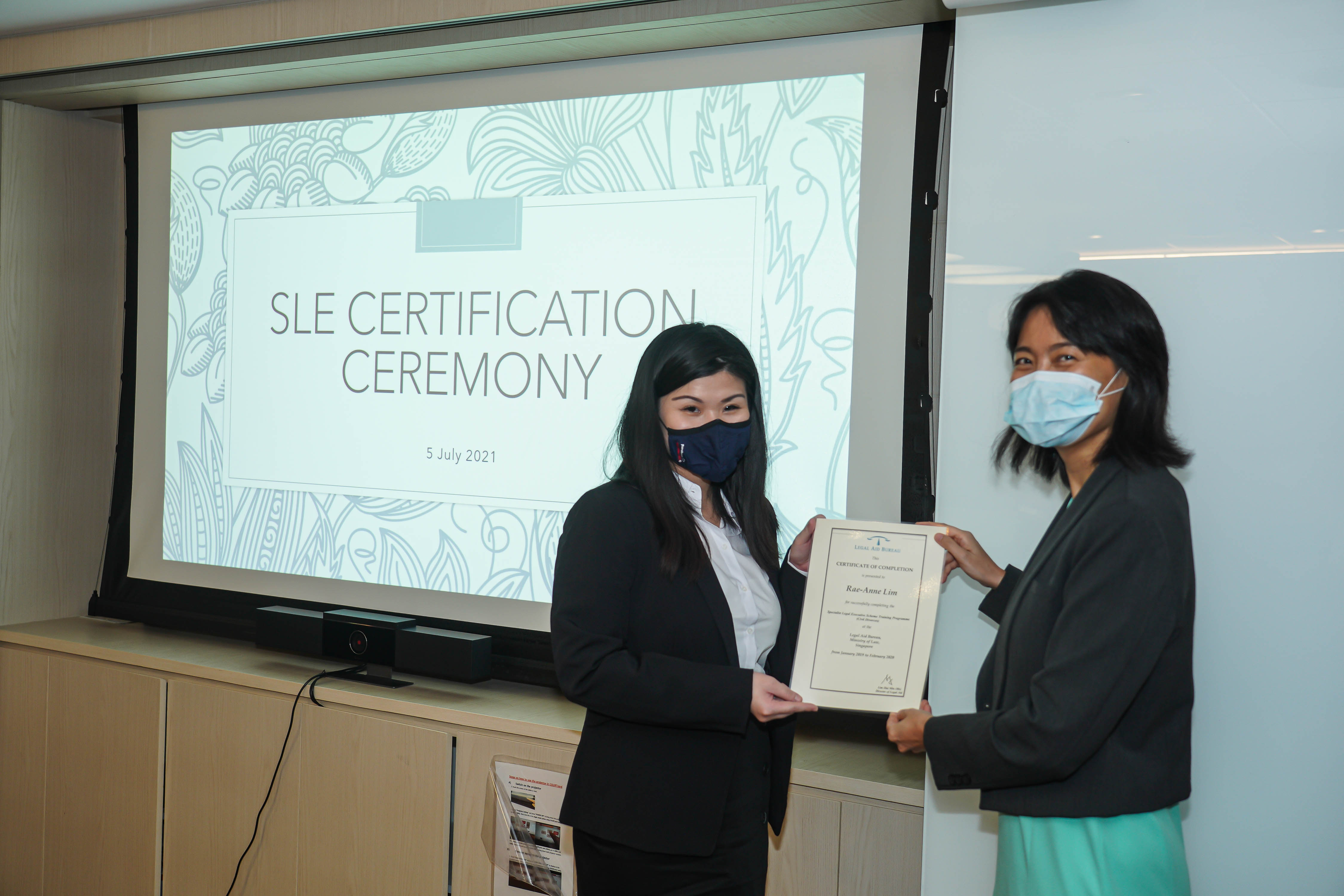 Rae-Anne (left) receiving her certificate from the Director of Legal Aid at MinLaw, Lim Hui Min, at the SLE Certification Ceremony in July 2021